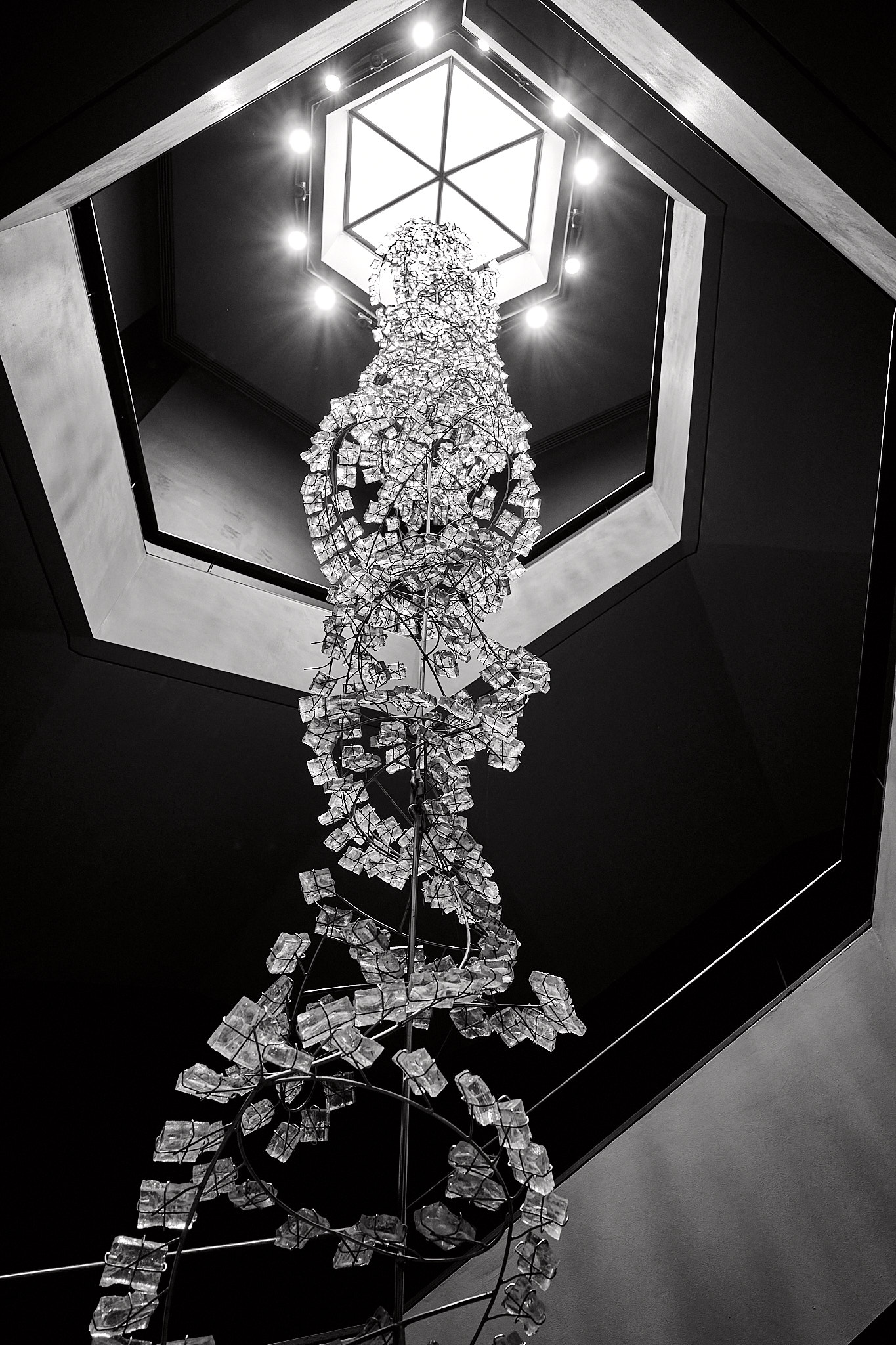 Ricoh GR III monochrome SDR JPEG of a suspended sculpture beneath a bright geometric atrium light.